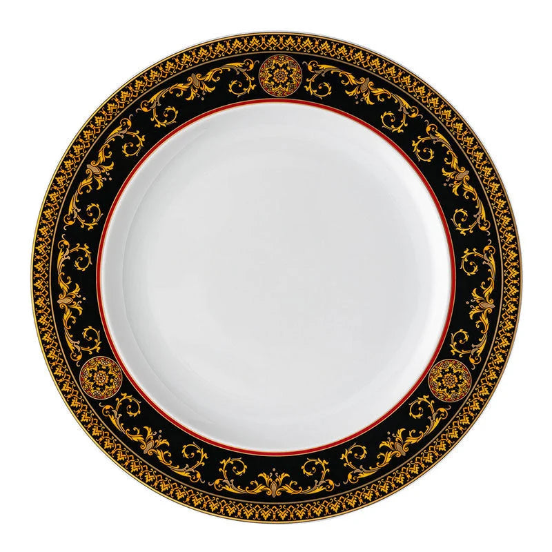 A round white Versace china plate with an ornate black and gold baroque-style border, featuring a thin red inner ring.