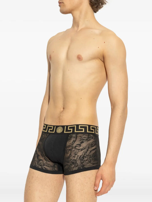 Man wearing black lace underwear with a detailed waistband on a white background.