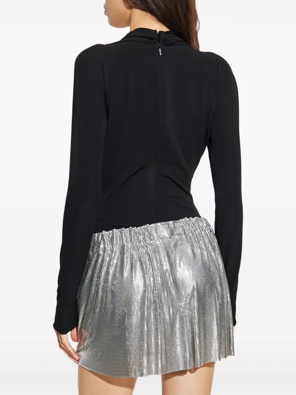 Woman wearing a black bodysuit and silver metal mesh skirt on a white background.
