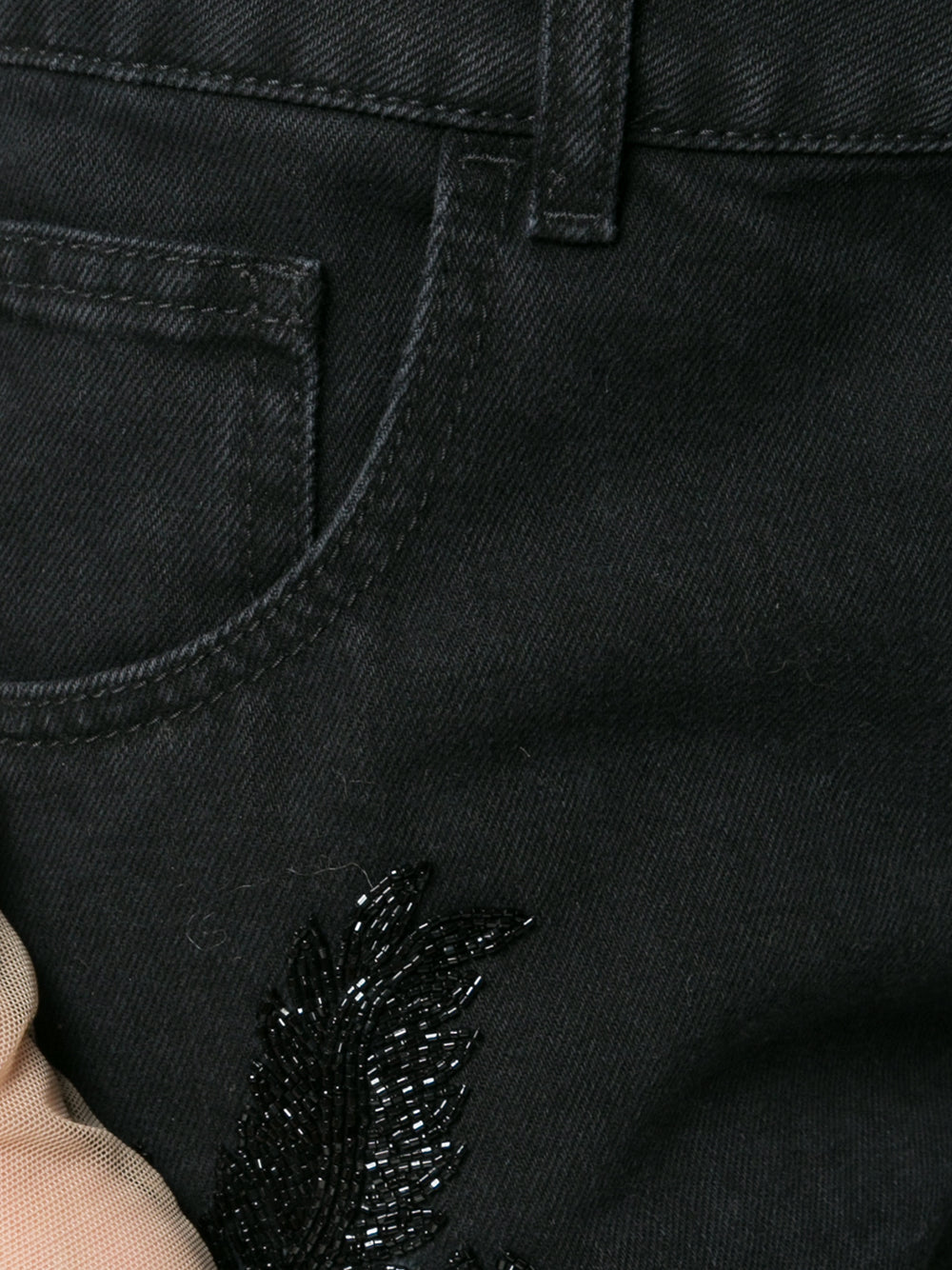 Close-up of black boyfriend jeans with beaded embellishments on both legs.