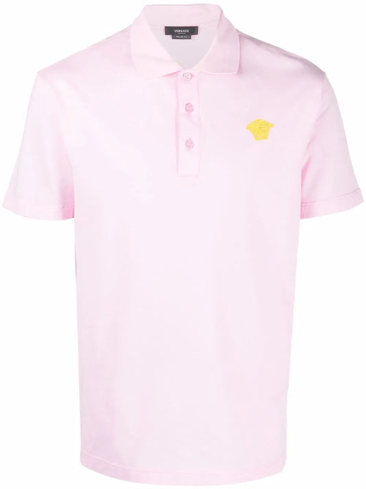 Pink polo shirt with a gold medusa logo.