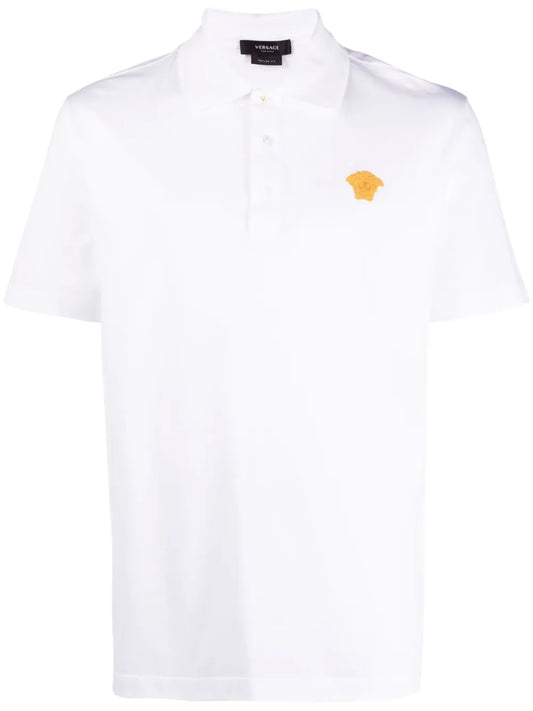 White polo shirt with a gold medusa on the chest.