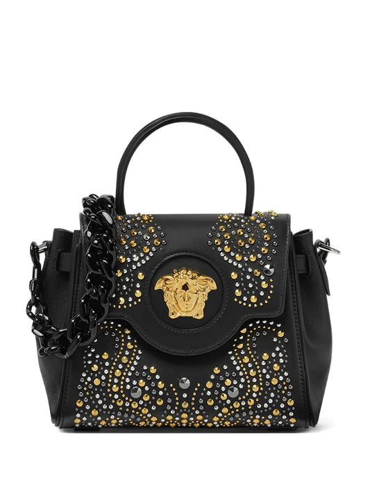 Black handbag with gold, silver and black embellishments on a white background.